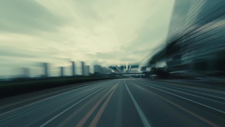 An exhilarating, motion-blurred point-of-view drive on a wide, empty highway through a modern city