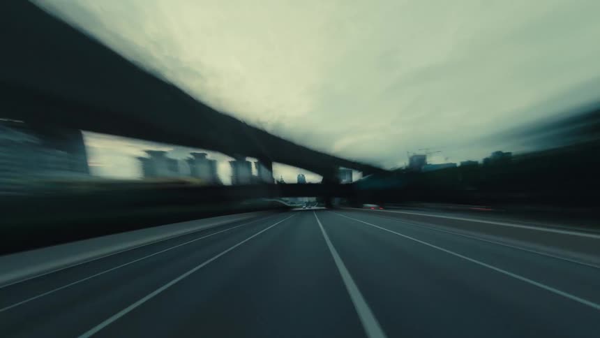 An exhilarating, motion-blurred point-of-view drive on a wide, empty highway through a modern city