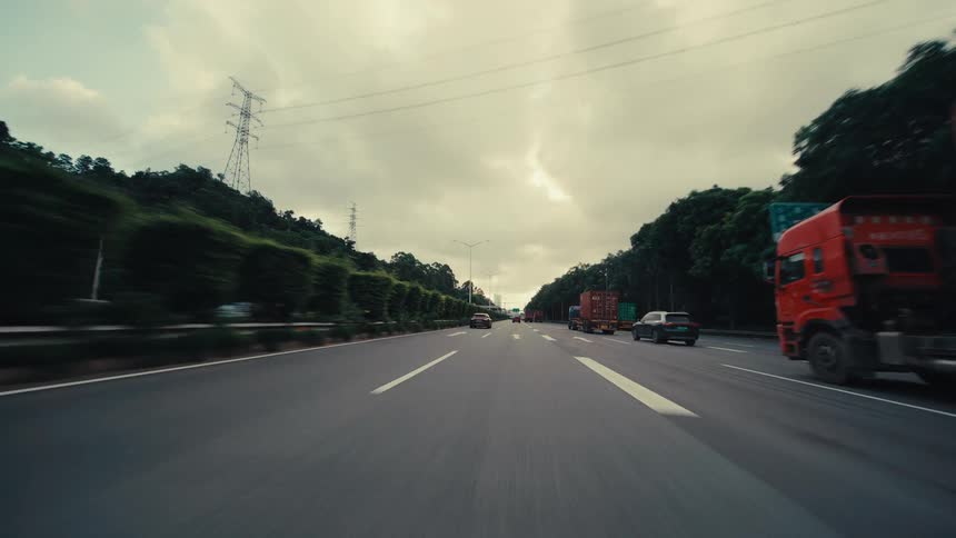 Dramatic point-of-view shot of a car driving at high speed on a busy highway under a cloudy sky