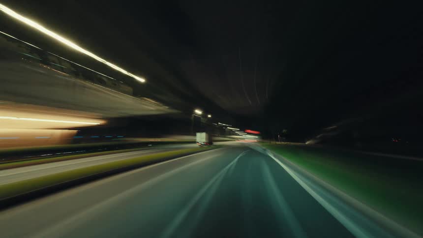 An exhilarating first-person hyper-lapse journey down a brightly lit city highway after dark, with motion blur creating streaks of light