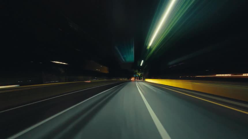 An exhilarating first-person perspective hyper-lapse of driving through a city at night with blurred light trails