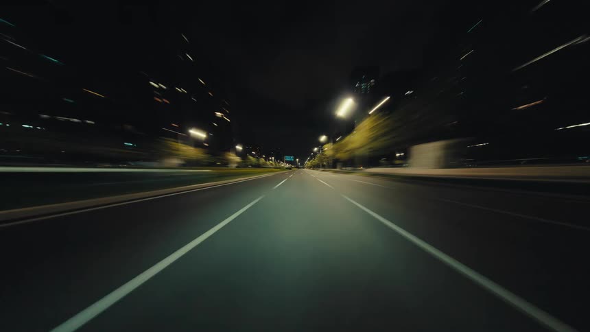 A thrilling point-of-view hyperlapse of driving through a city at night with motion-blurred lights creating a futuristic effect
