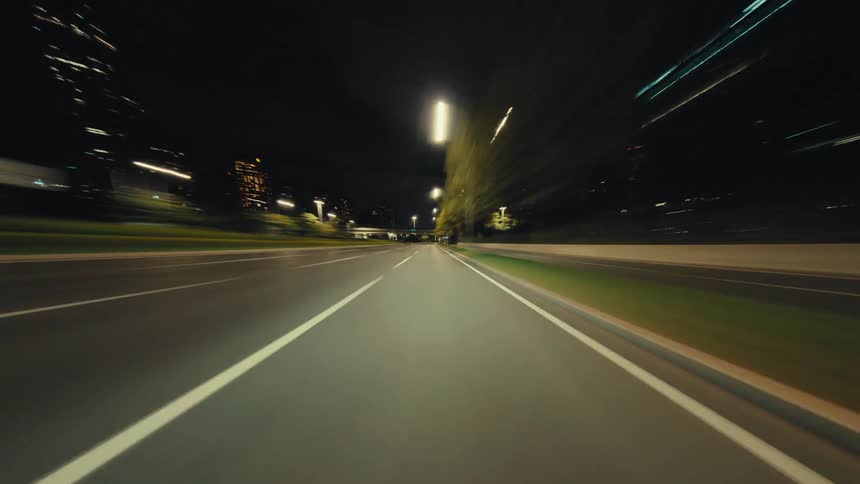 A thrilling point-of-view hyperlapse of driving through a city at night with motion-blurred lights creating a futuristic effect