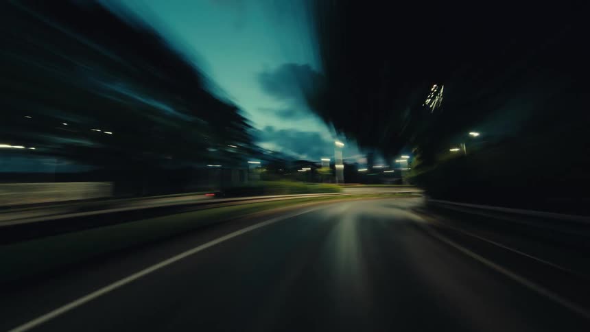 A surreal point-of-view time-lapse captures a high-speed drive through a city at dusk, with urban lights creating streaks and motion blur