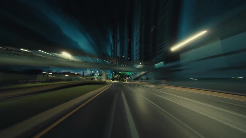 A surreal point-of-view time-lapse captures a high-speed drive through a city at dusk, with urban lights creating streaks and motion blur