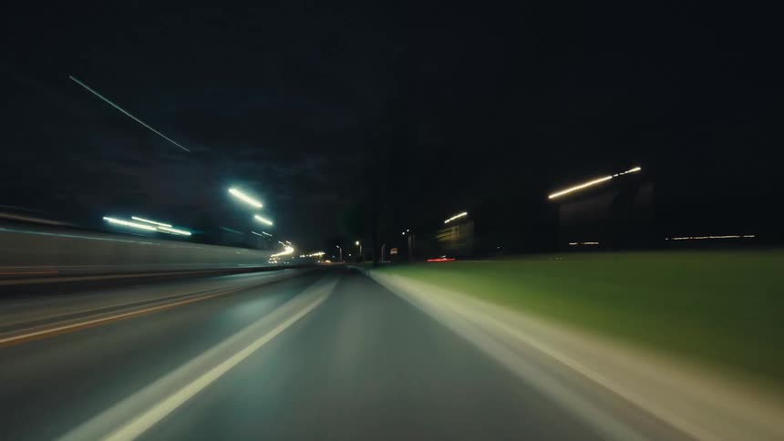 A thrilling first-person perspective hyperlapse captures a high-speed drive through a modern city at night, with streetlights blurring into streaks of light