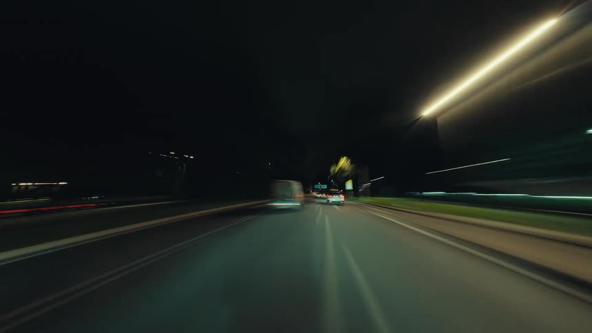 POV hyperlapse of a car speeding through a modern tunnel and along city highways at night, creating colorful light streaks