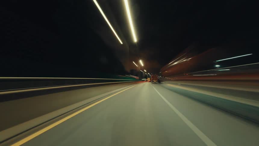 Mesmerizing hyper-lapse captures the blur of city lights while driving down an empty highway at night