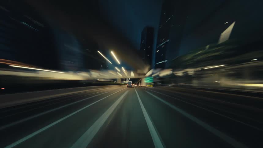 A dynamic point-of-view time-lapse of driving through a futuristic city highway at night, surrounded by streaking light trails
