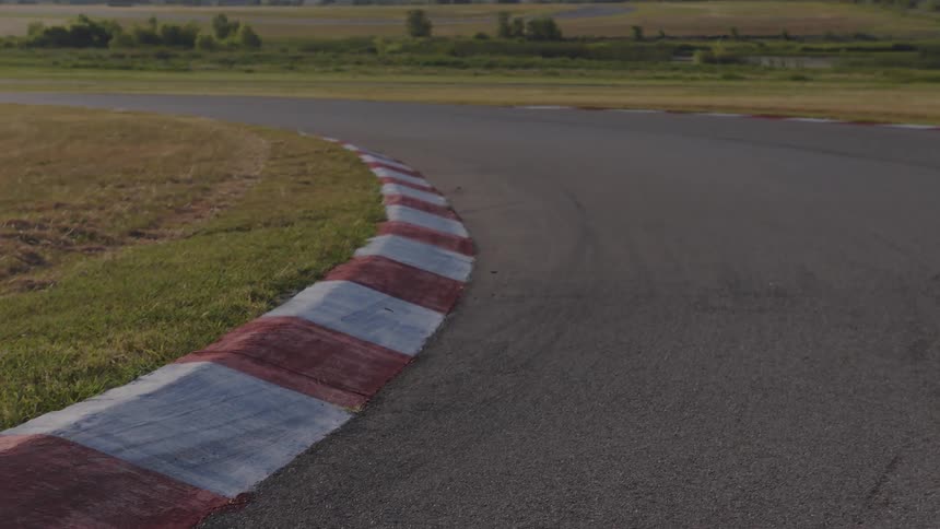 A static close-up shot of the red and white curbing on a turn of an empty race track