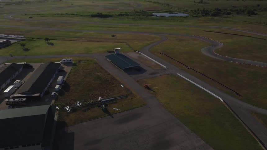 A slow ascending aerial view of an empty race track and its facilities surrounded by green fields