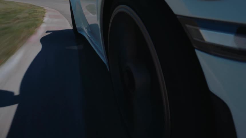 A close-up shot of a white sports car's spinning wheel as it speeds around a sunny racetrack