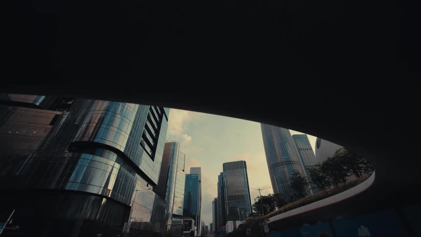 A smooth tracking shot from under a futuristic bridge reveals the modern glass skyscrapers of a city financial district