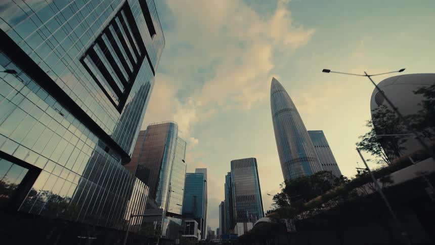 A smooth tracking shot from under a futuristic bridge reveals the modern glass skyscrapers of a city financial district