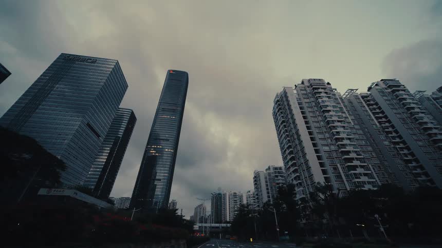 A moody low-angle point-of-view shot driving through the streets of a modern city with towering skyscrapers