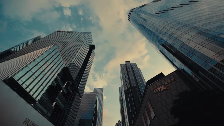 A dramatic opening reveal of towering modern skyscrapers in a city, filmed from a low-angle perspective while moving slowly forward