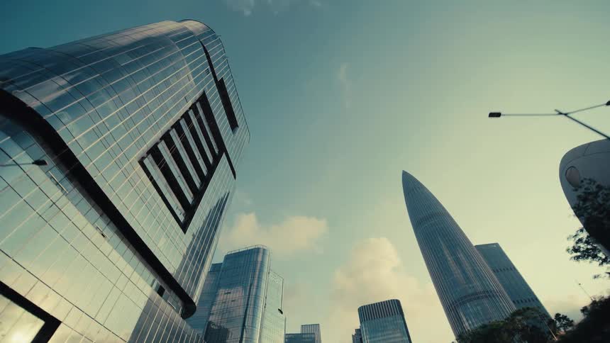 A smooth tracking shot reveals a futuristic city skyline with towering glass skyscrapers from beneath a modern architectural structure
