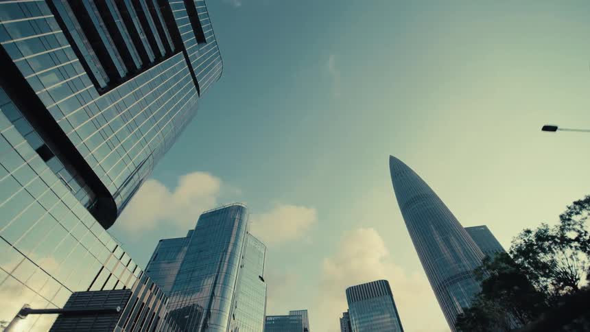 A smooth tracking shot reveals a futuristic city skyline with towering glass skyscrapers from beneath a modern architectural structure