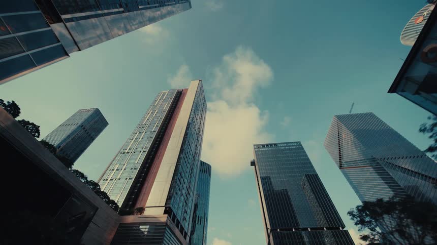 A slow-motion, low-angle forward tracking shot through a modern city filled with impressive glass skyscrapers