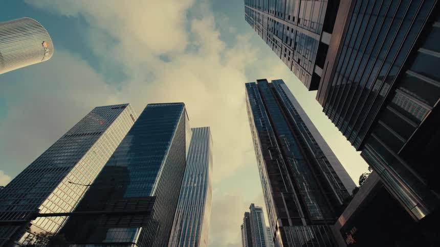 A smooth, low-angle journey through a modern metropolis reveals towering glass skyscrapers reaching for the sky