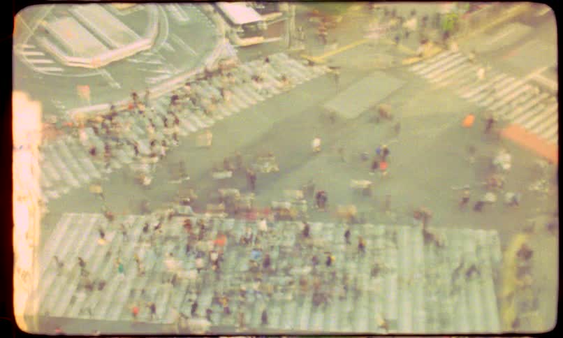 Retro 8mm film captures a time-lapse of pedestrians swarming a busy city intersection from above