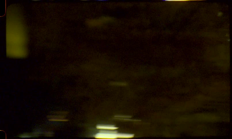 Vintage 8mm film captures an abstract, chaotic motion blur of yellow-green lights at night