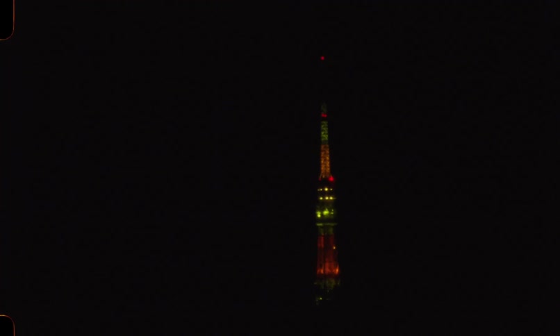 Vintage 8mm film captures the Tokyo Tower at night before panning rapidly into a blur of abstract city lights