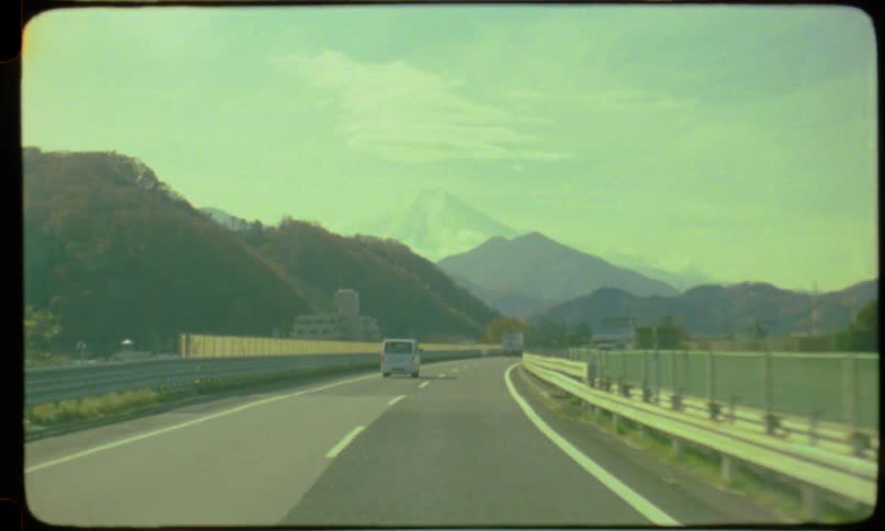 A vintage film perspective of driving on a Japanese highway with Mount Fuji visible in the distance