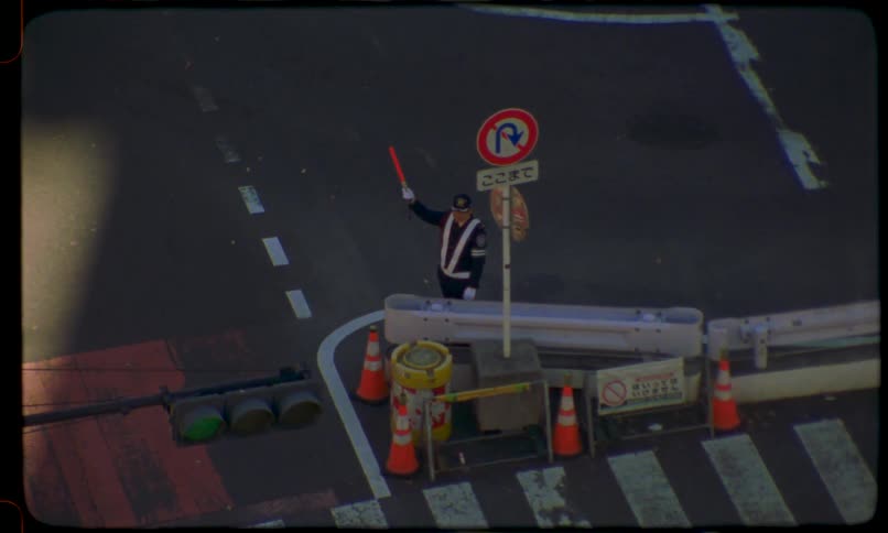 Vintage film shot from above of a Japanese traffic controller standing at an intersection directing cars