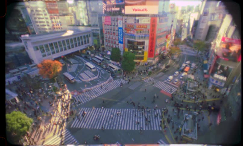 A vintage, film-style high-angle view of the bustling Shibuya Crossing in Tokyo, Japan, with crowds of people and cars filling the intersection
