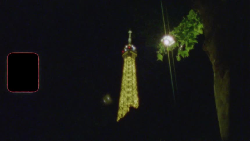 A vintage Super 8 film captures the illuminated Eiffel Tower sparkling against the dark night sky in Paris