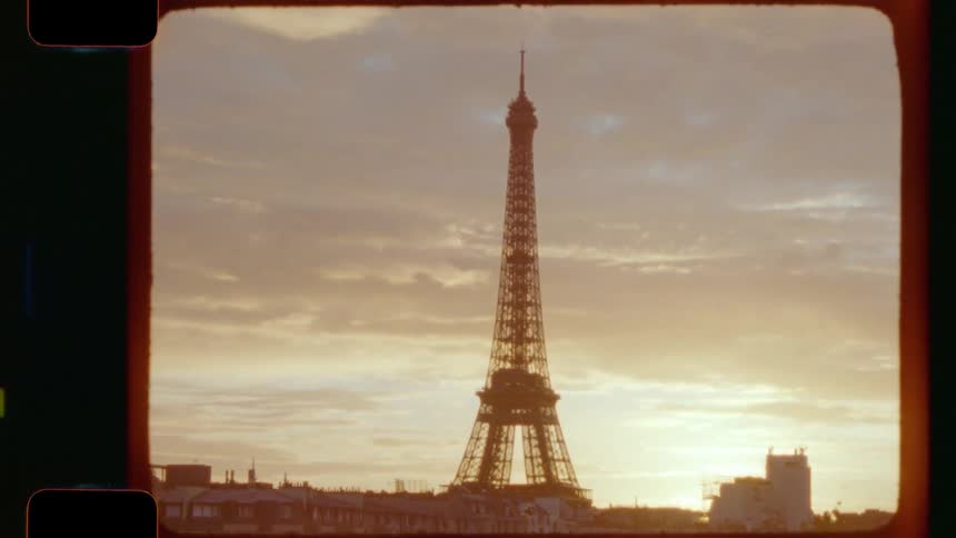 A vintage 16mm film captures the Eiffel Tower silhouetted against a dreamy golden hour sunrise over the rooftops of Paris
