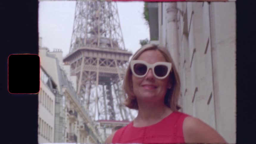 A stylish woman in sunglasses smiles for a vintage film portrait on a street in Paris with the Eiffel Tower in the background