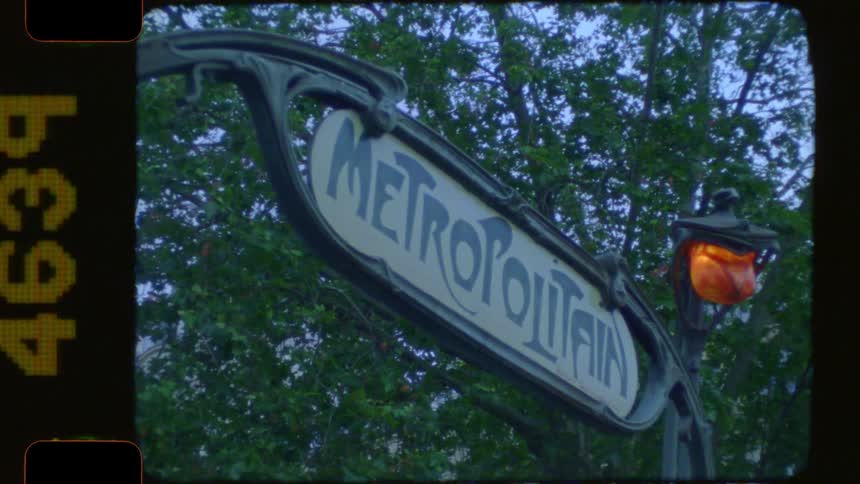 A vintage-style shot captures the iconic Art Nouveau Metropolitain sign for the Paris Metro at dusk