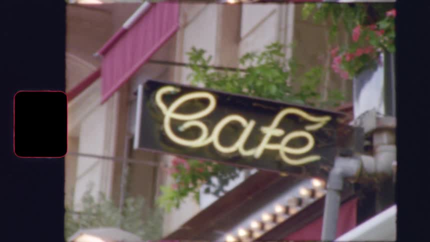 A nostalgic super 8 film zooms in on a classic neon 'Cafe' sign on a charming Parisian street