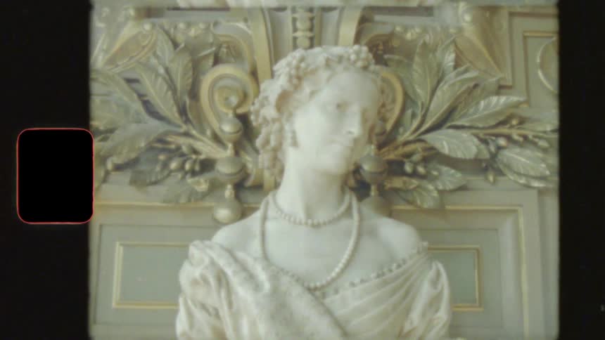 Vintage film footage shows a detailed marble bust of a noblewoman with an ornate, gilded wall panel behind her