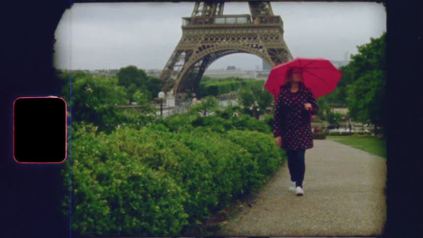 Vintage film captures a woman with a red umbrella walking through a Parisian park with the Eiffel Tower in the background on a rainy day