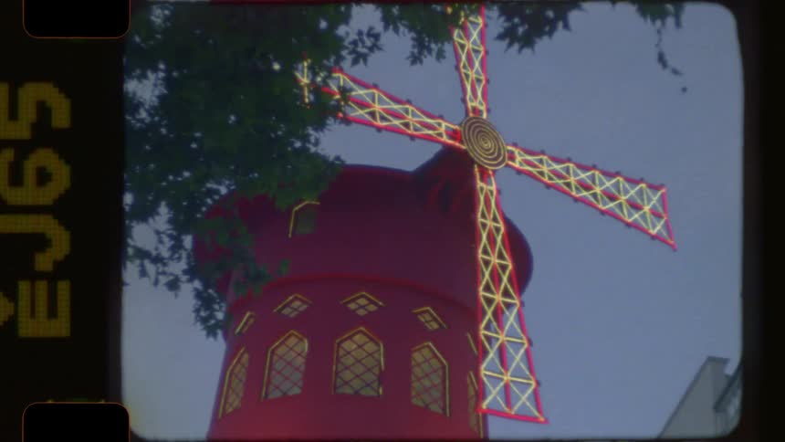 Vintage film footage of the iconic Moulin Rouge in Paris at dusk, showing its neon sign and red windmill