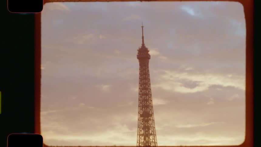 Vintage 16mm film shot of the Eiffel Tower in Paris, tilting up to the sky during a beautiful golden hour sunset