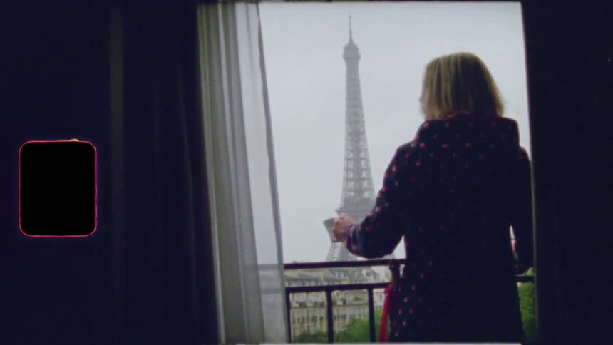 A woman in a robe sips her morning coffee on a balcony, admiring the view of the Eiffel Tower in Paris on a vintage film