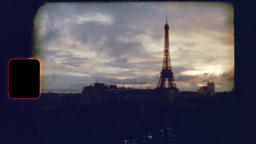A vintage 8mm film captures a nostalgic view of the Paris skyline and Eiffel Tower at dusk as city lights begin to glow