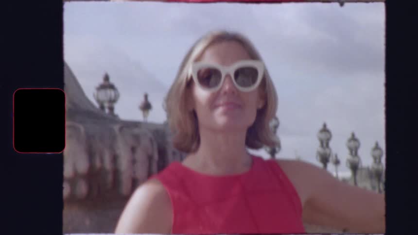 Vintage 8mm film captures a stylish woman in a red dress and sunglasses posing on the Pont Alexandre III bridge in Paris, France