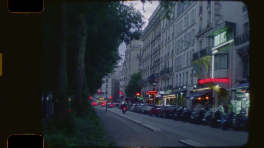 A vintage film captures the atmospheric streets of Paris at dusk, with neon signs glowing and scooters parked along the busy boulevard