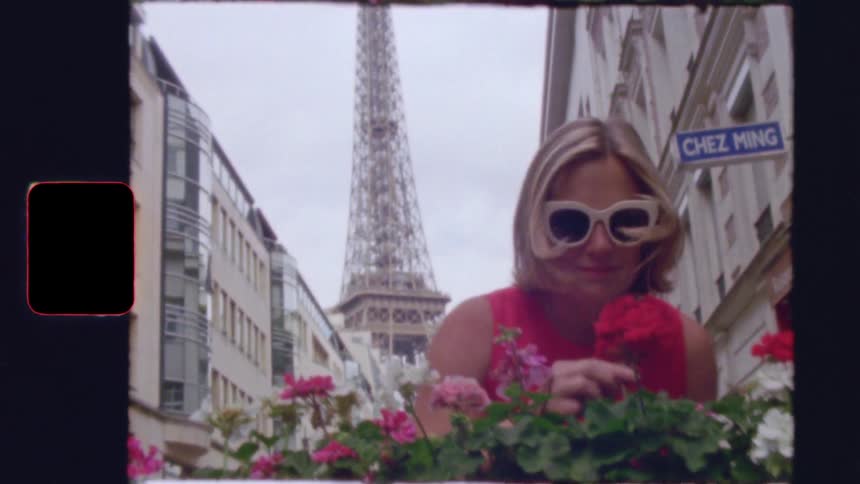 Vintage-style footage shows a stylish woman smelling flowers on a Parisian street with the Eiffel Tower in the background