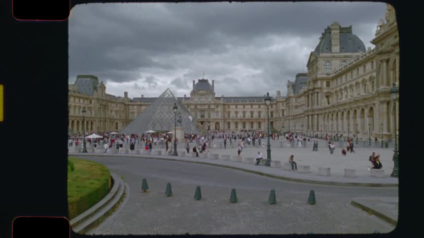 Vintage-style 16mm film footage of tourists milling about the Louvre Museum and its famous glass pyramid on a cloudy day in Paris