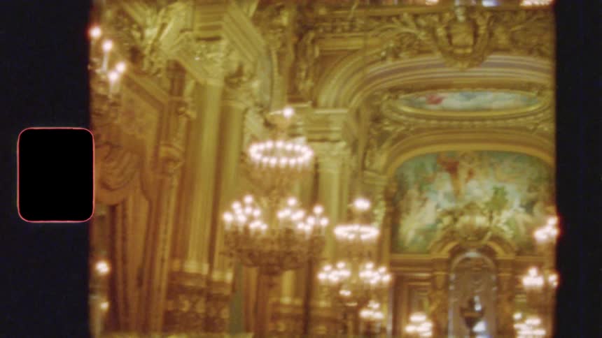 A vintage Super 8mm film shot slowly reveals the opulent golden interior of a grand hall filled with glowing chandeliers