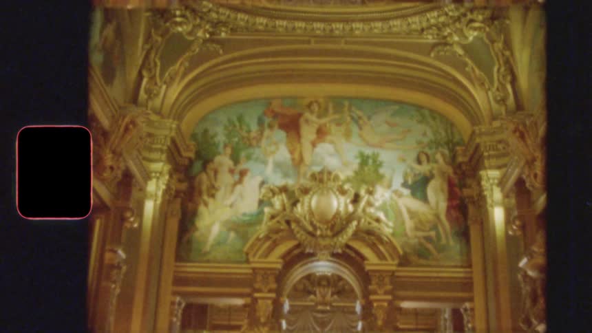 Vintage 8mm film pans from an opulent golden chandelier to an ornate mural on the wall of a historic European palace or opera house