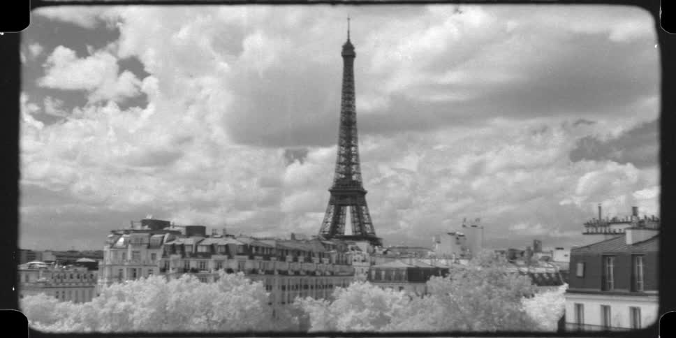 A vintage, 16mm black and white, time-lapse shot of the Eiffel Tower in Paris with dramatic clouds moving across the sky