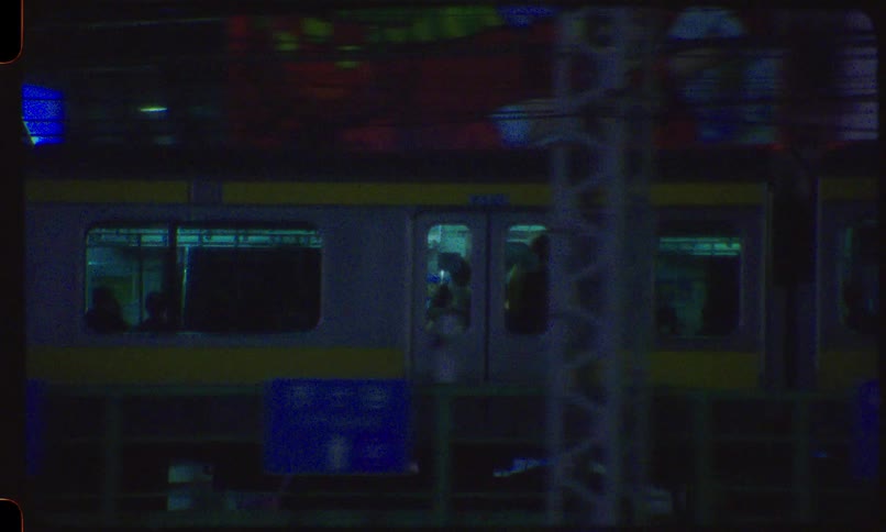 A vintage 8mm film captures a train moving through a neon-lit city at night