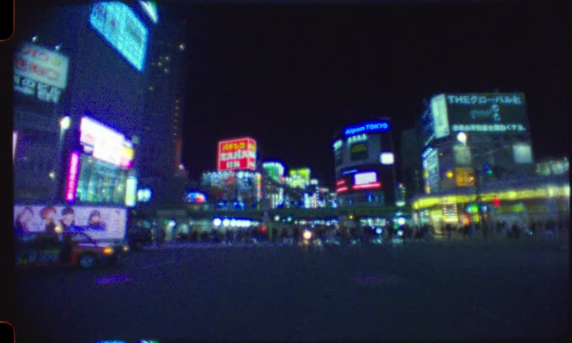 Dreamy vintage film footage captures the vibrant neon-lit streets of a bustling Tokyo intersection at night